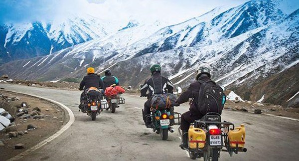 Motorcycle rider crossing high mountain pass in Ladakh scenic landscape during Leh Ladakh bike trip